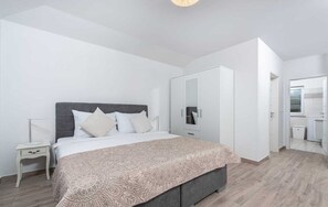Een moderne slaapkamer met een bed, nachtkastje, kledingkast en uitzicht op de badkamer.