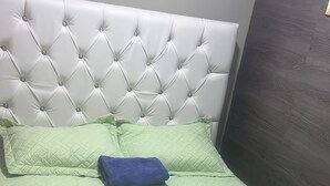 A bed with a tufted headboard, a green quilt, and two pillows. - Dilias house RANCH (Sabana Larga)