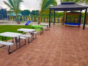 Un patio al aire libre con mesas de picnic y una zona de estar cubierta.
