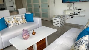 A modern living room with a white sofa, a coffee table, and a TV mounted on the wall. - Conchita de Mar (Punta Cana)