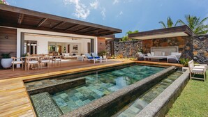 Una casa moderna con piscina, terraza de madera y zona de estar al aire libre.
