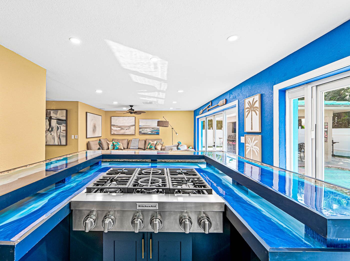 A kitchen with a gas stove, a sofa, and a view of a pool.