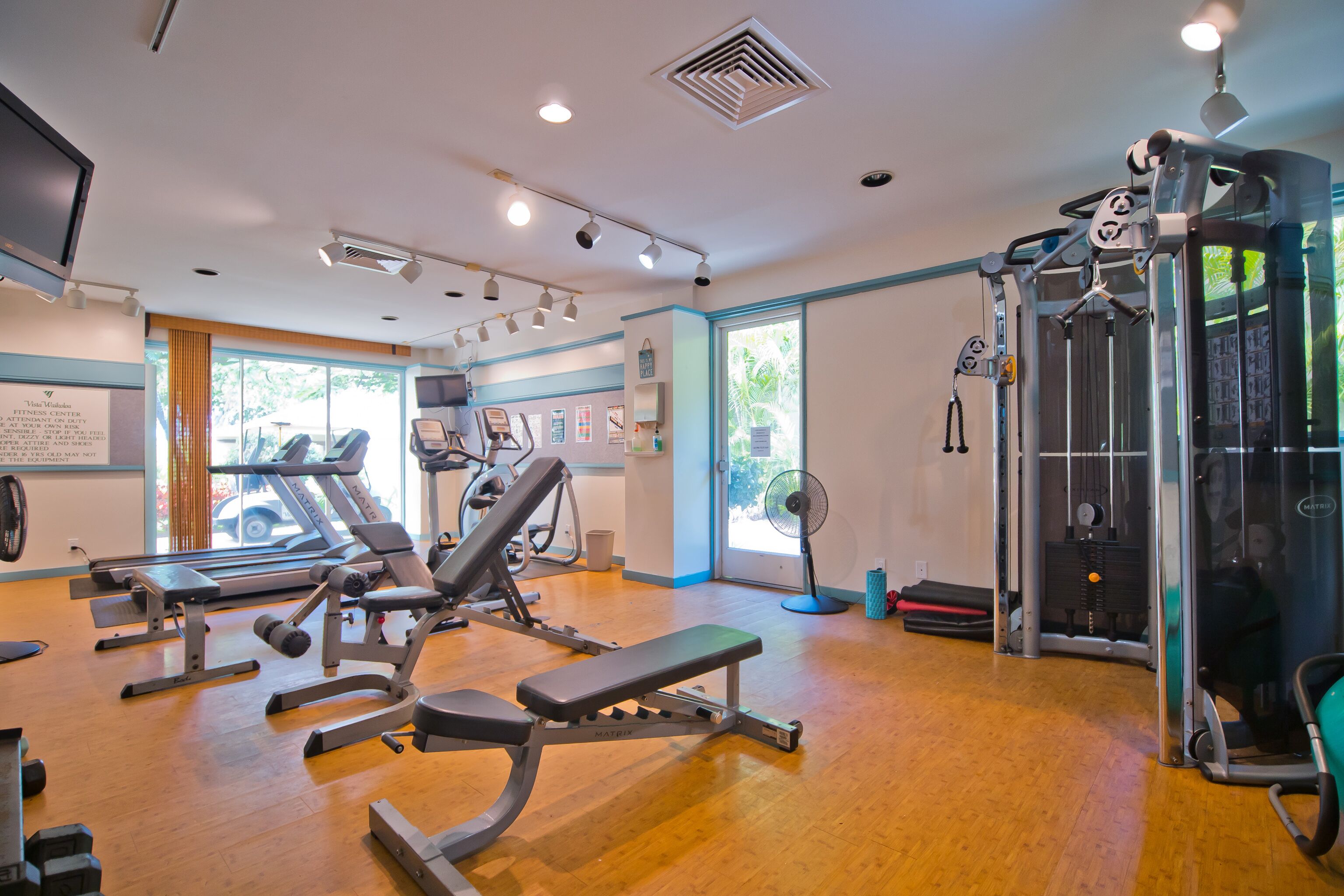 A gym with various exercise equipment, a treadmill, and a fan.