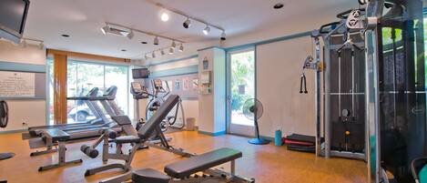 A gym with various exercise equipment, a treadmill, and a fan.