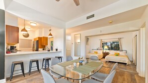 Una cocina moderna con comedor, un dormitorio con ventana grande y una sala de estar con sofá y mesa de centro.