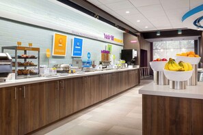 Een ontbijtbalk met een bakkerijgedeelte, een fruitschaal en een bord met 'Top 10 ontbijten'.