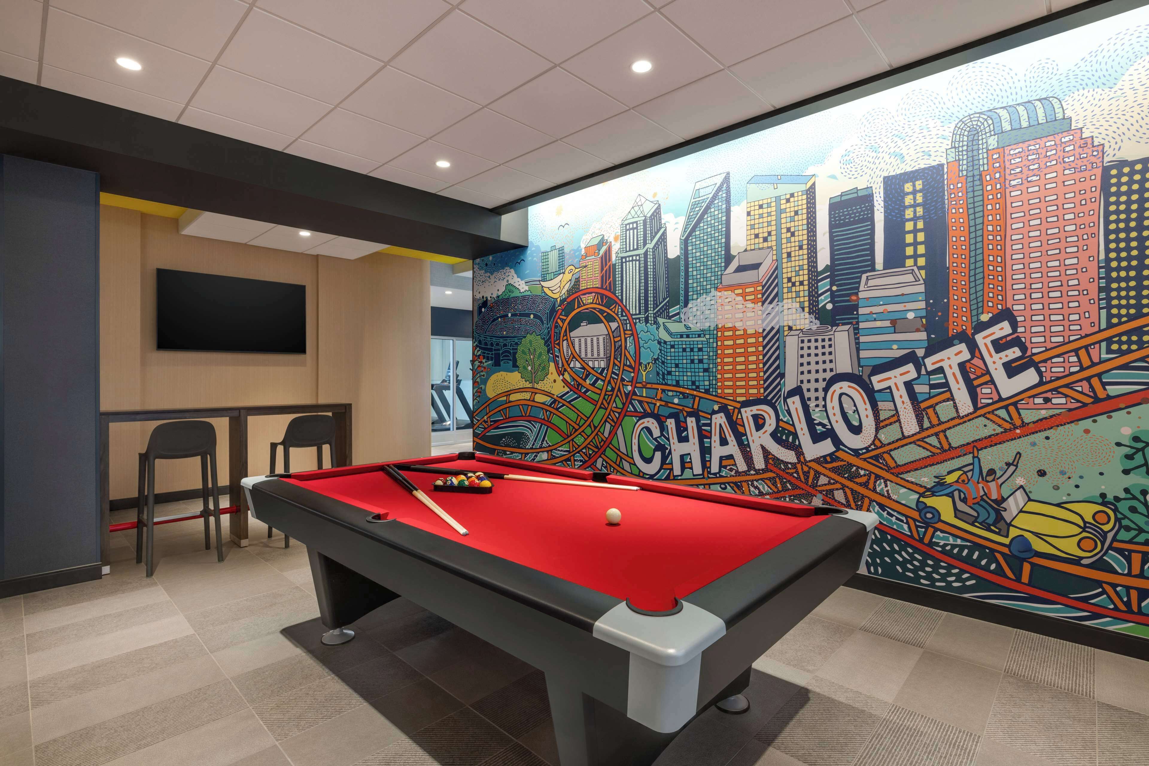 A pool table with a red felt surface, a billiards cue, and a white cue ball.