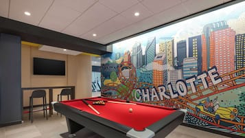 A pool table with a red felt surface, a billiards cue, and a white cue ball.