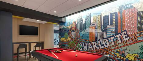 A pool table with a red felt surface, a billiards cue, and a white cue ball.