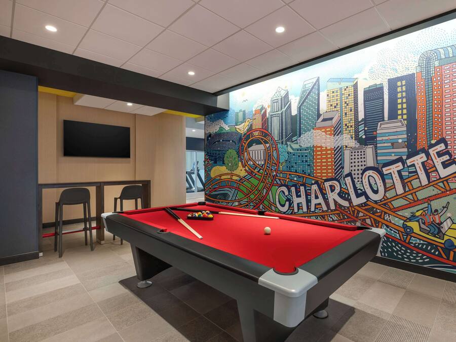 A pool table with a red felt surface, a billiards cue, and a white cue ball.