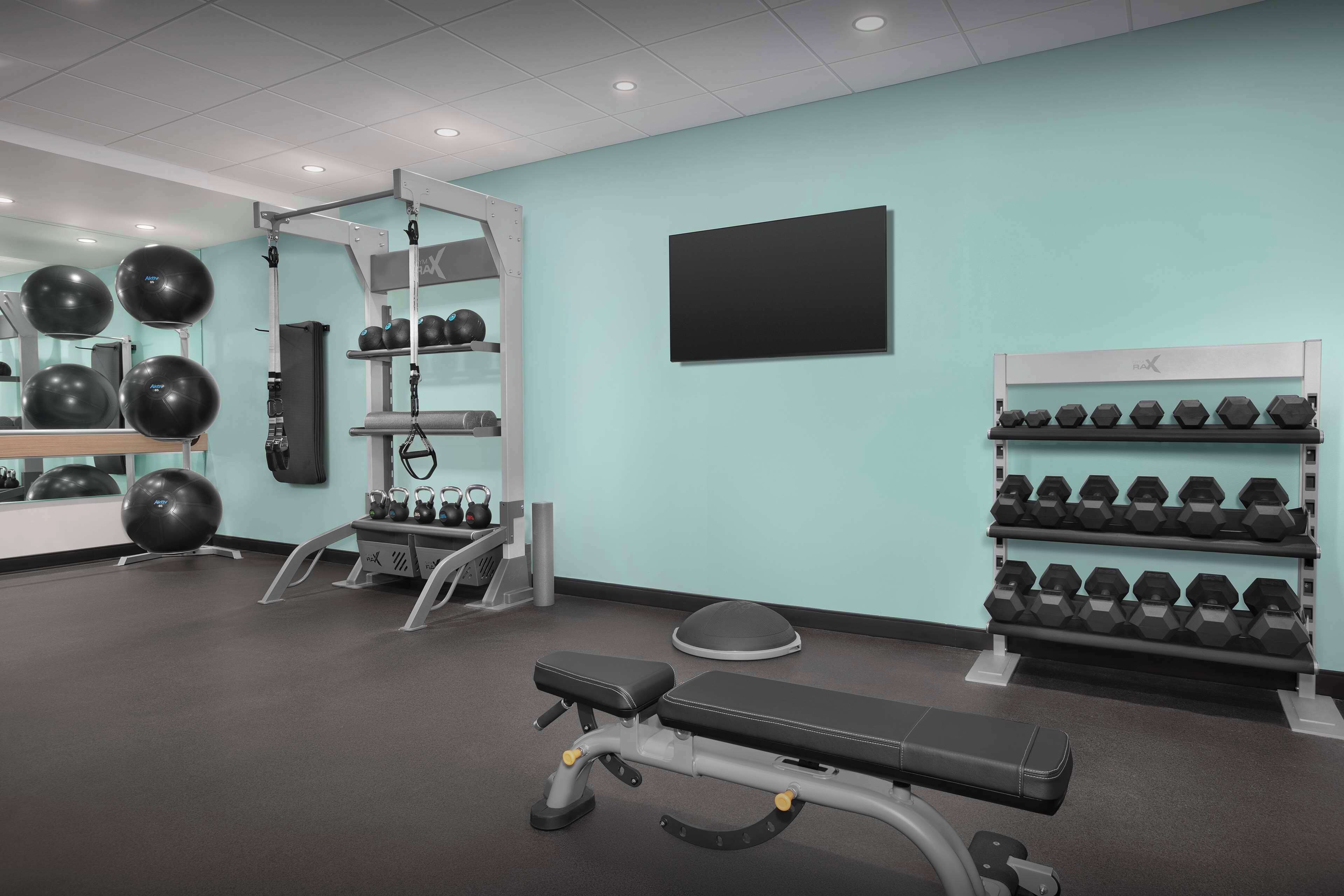 A gym with exercise equipment, a bench, and dumbbells.