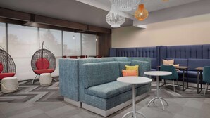 A modern lounge area with a blue sofa, round tables, and hanging chairs. - Tru By Hilton Jackson, Tn (Jackson)