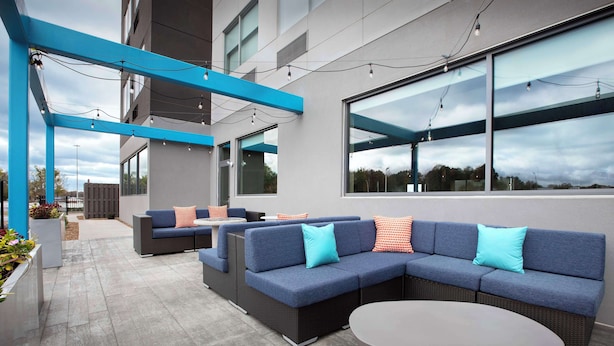 An outdoor seating area with a sectional sofa, round table, and blue accents. - Tru By Hilton Jackson, Tn (Jackson)