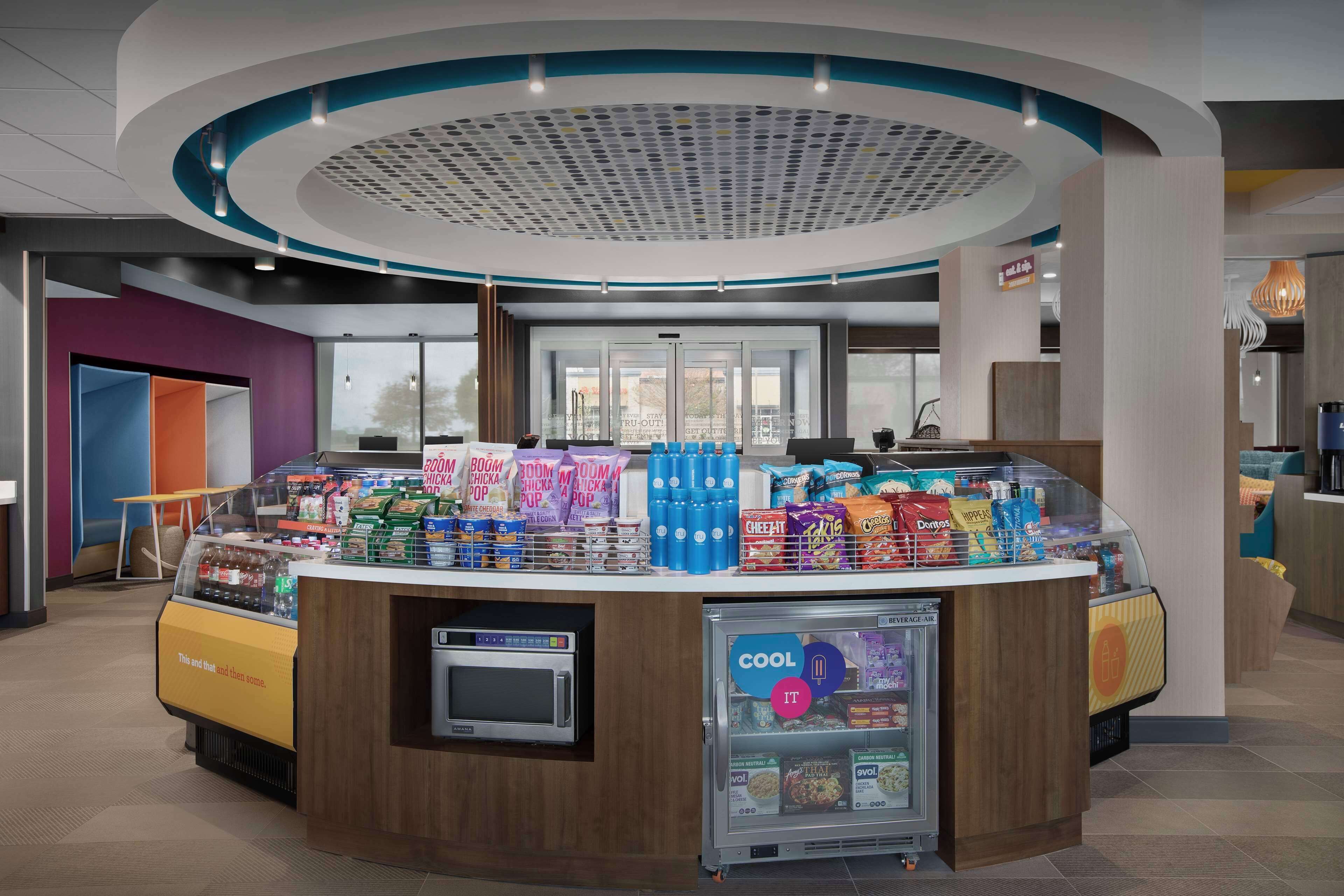 A self-service beverage station with a microwave, a refrigerated display, and a variety of snacks.