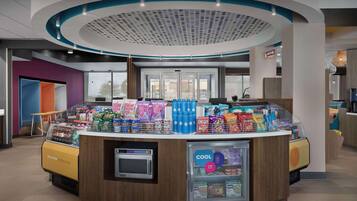 A self-service beverage station with a microwave, a refrigerated display, and a variety of snacks.