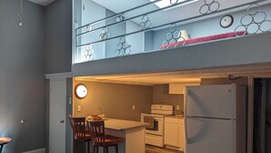 A compact kitchen with a central island, a refrigerator, and a dining area with chairs. - Cozy Loft Hideaway in Robinson (Robinson)