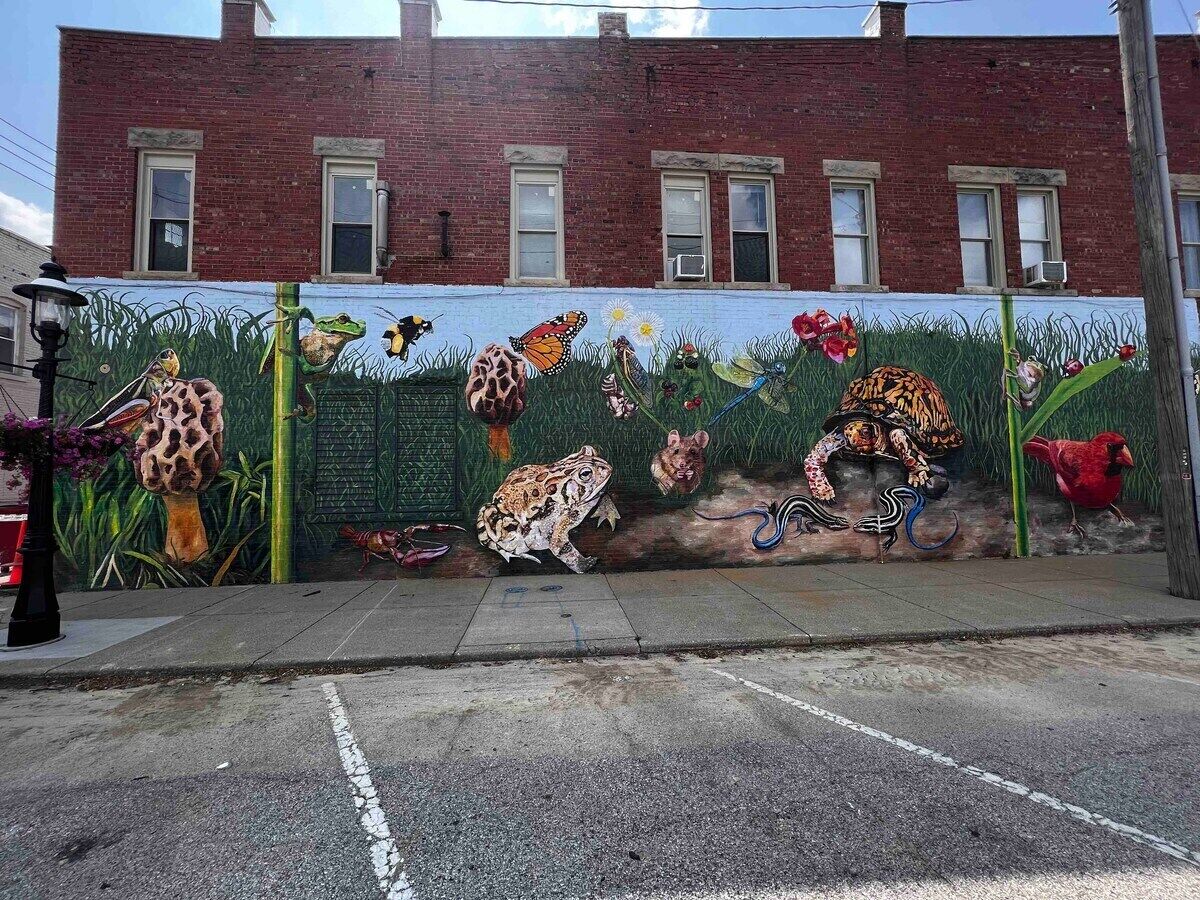 Un mural en una pared de edificio con varios animales y flores.