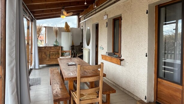 A wooden dining area with a table and benches, a ceiling fan, and a view of the outside.