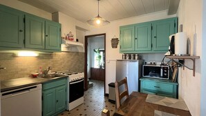 A compact kitchen with teal cabinets, a gas stove, a microwave, and a refrigerator.