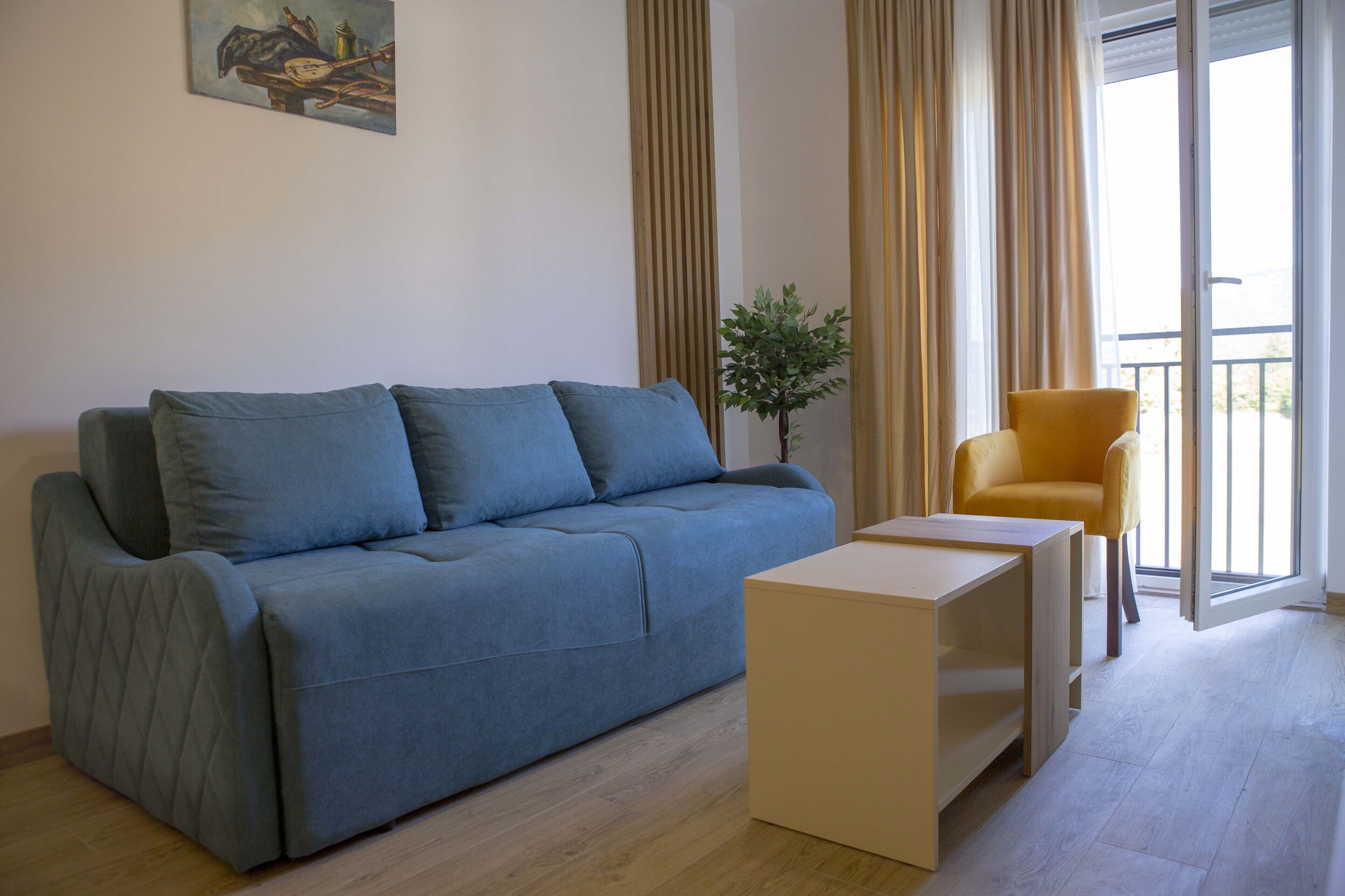 A modern living room with a blue sofa, a small wooden table, and a yellow armchair.