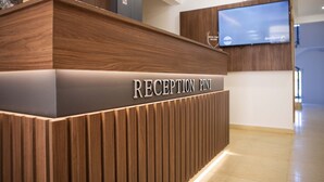A reception desk with a wooden finish and a digital screen above it. - Apart Hotel Gondola Kolasin (Kolašin)