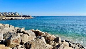 A coastal scene with large rocks in the foreground and a clear blue sky. - Experience Classic New England-walk to beach&shops (Rockport)