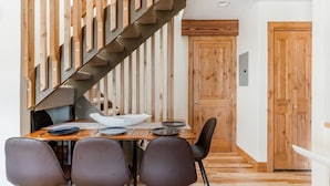 Un comedor con una mesa de madera, cuatro sillas y una escalera con barandillas de madera.