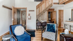 A spacious living area with a high ceiling, wooden beams, a dining area with chairs, and a bar counter. - VAIL HAUS: 2 Bedroom Penthouse + Loft on Vail Bus Route (Vail)