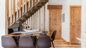 A dining area with a wooden table, four chairs, and a staircase with wooden railings. - VAIL HAUS: 2 Bedroom Penthouse + Loft on Vail Bus Route (Vail)