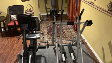 A home gym with exercise equipment, a rug, and a window with curtains.