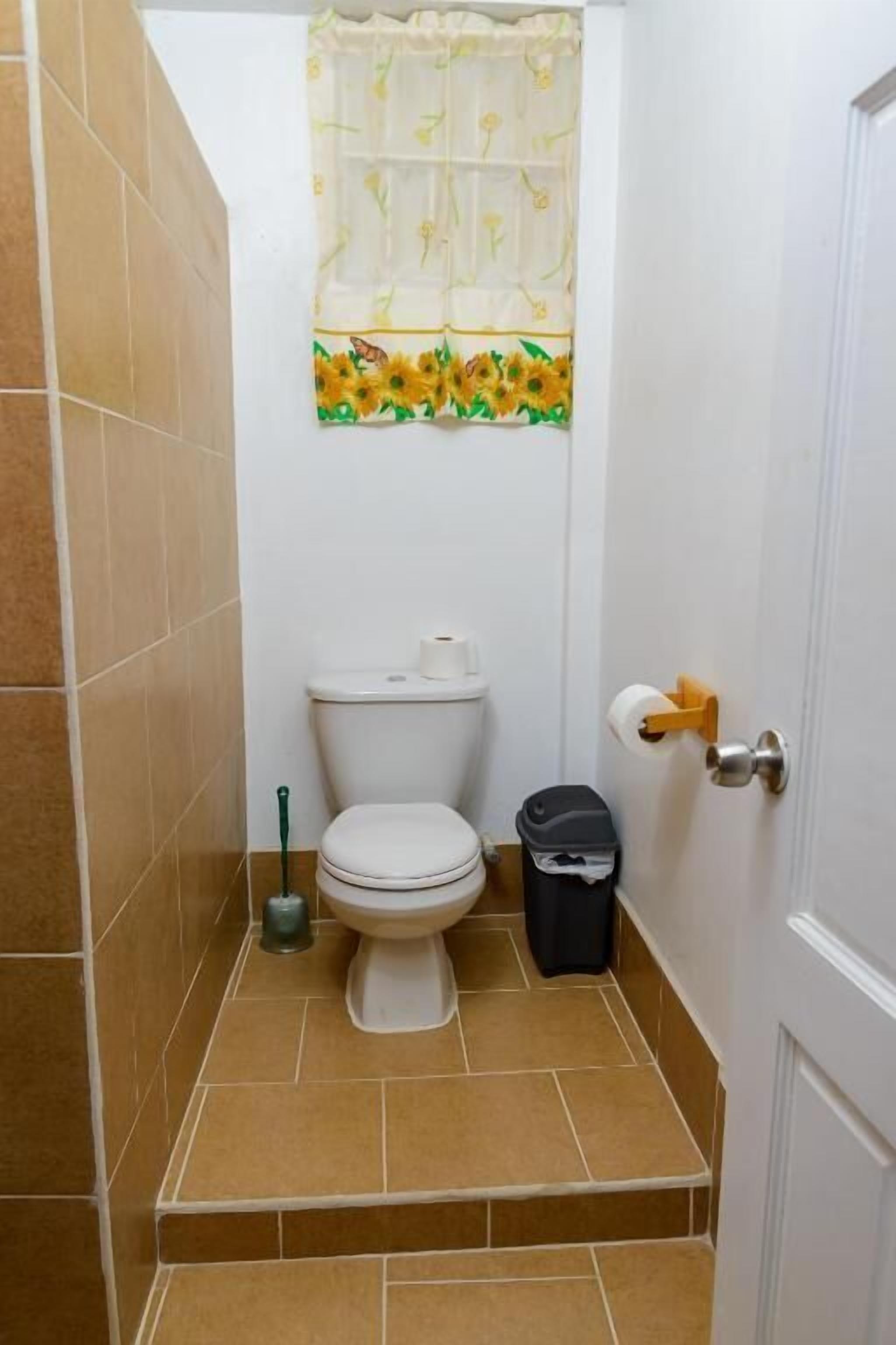 Pieni kylpyhuone, jossa on wc, roskakori ja wc-paperiteline.