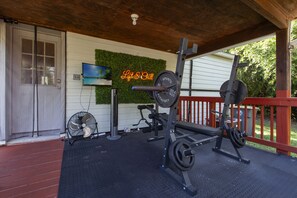 Ett utomhusgym med träningsredskap, en fläkt och en tv monterad på en vägg.