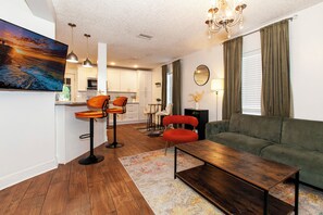 A modern living room with a green sofa, two orange chairs, a wooden coffee table, and a colorful rug. - Stylish 4BR Jacksonville Home , Sleeps 8 (Jacksonville)
