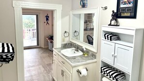 A bathroom with a white vanity, a sink, a mirror, and a towel rack. - Utila Suite Sleeps 6 (Utila)