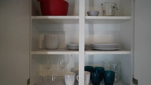 A kitchen cabinet with shelves holding various kitchenware.