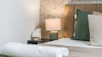 A neatly made bed with a white comforter and a folded white towel.