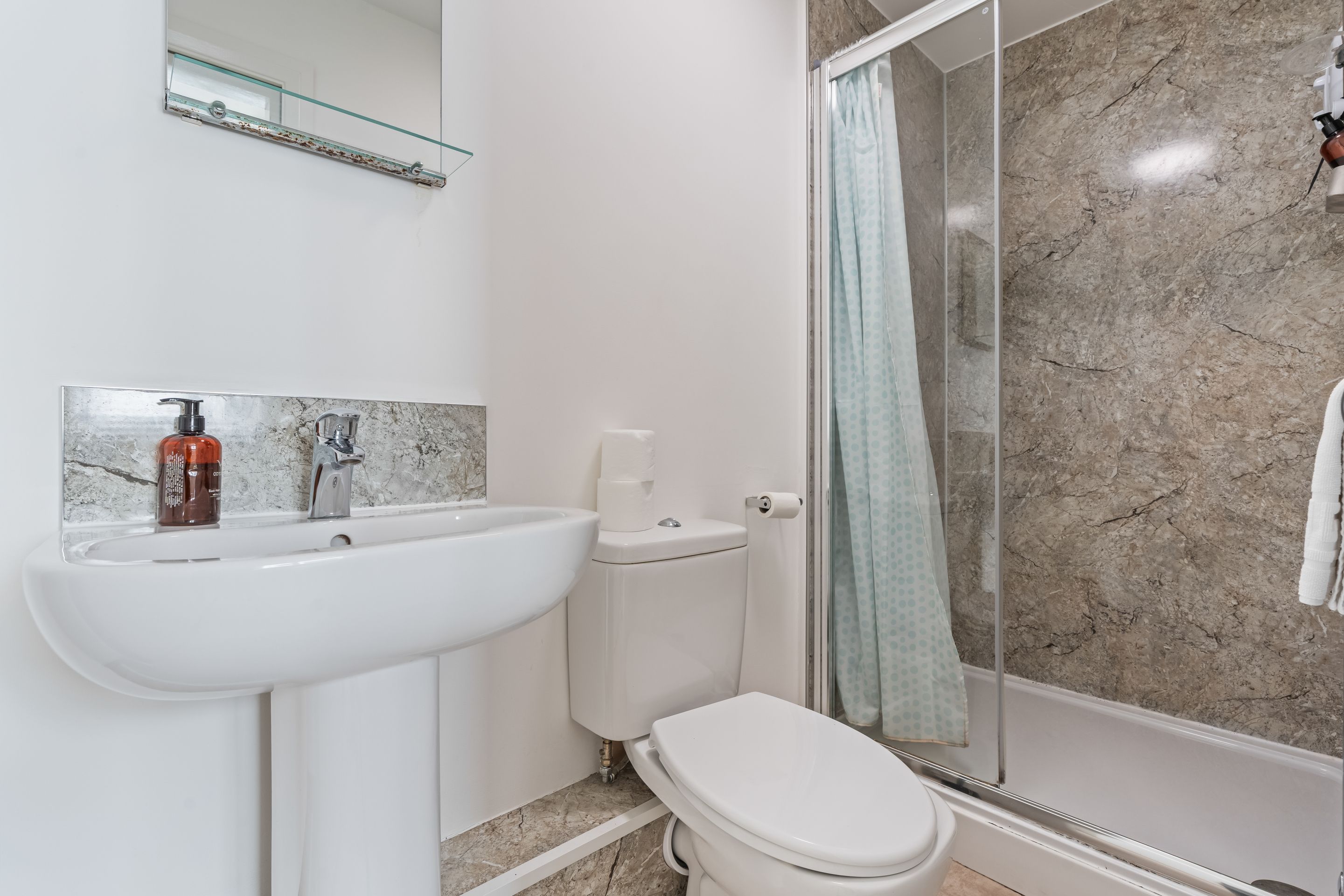 Un baño con un lavabo blanco, un inodoro y una ducha con puerta de cristal.