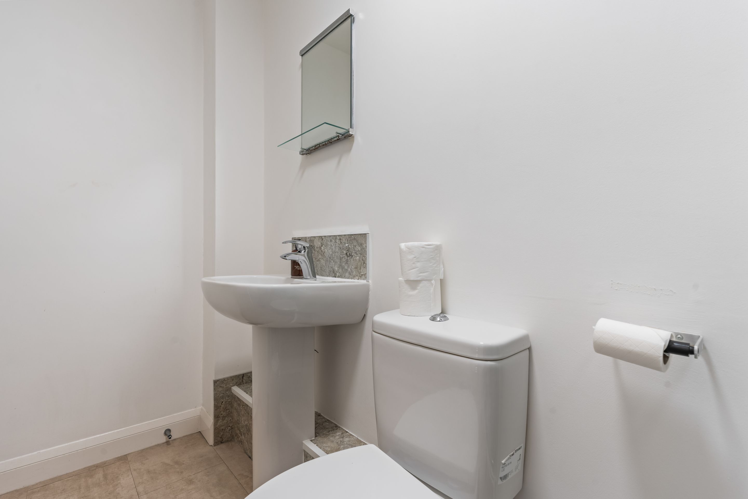 A bathroom with a white sink, a toilet, and a mirror.