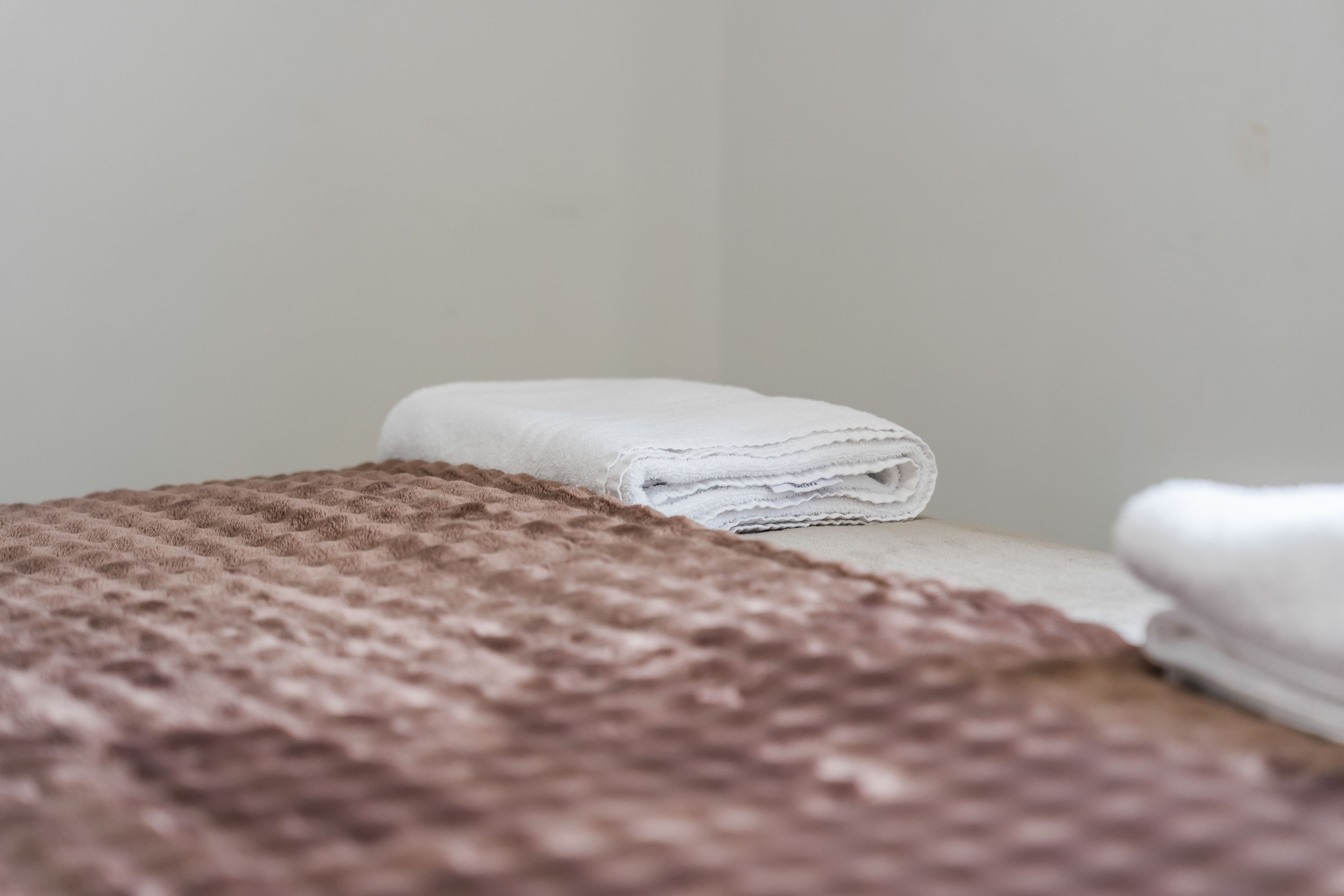 Un ensemble de serviettes soigneusement disposées sur un lit recouvert d’une couverture marron à texture.