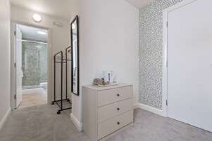 A bathroom with a white toilet, a shower area, and a mirror.