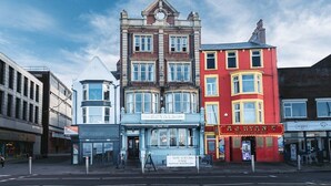 Una hilera de edificios, con un edificio rojo destacado identificado como 'The Royal Hotel'.