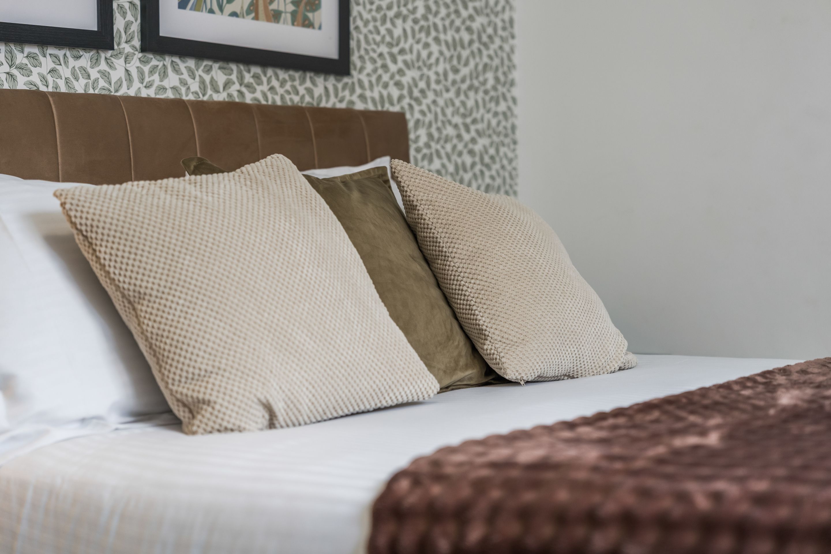 A bed with two pillows, a headboard, and a patterned wall.