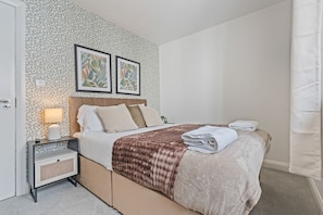 A hotel room with a bed, a nightstand, a lamp, and two framed pictures on the wall. - The Royal Bar & Shaker (Morecambe)
