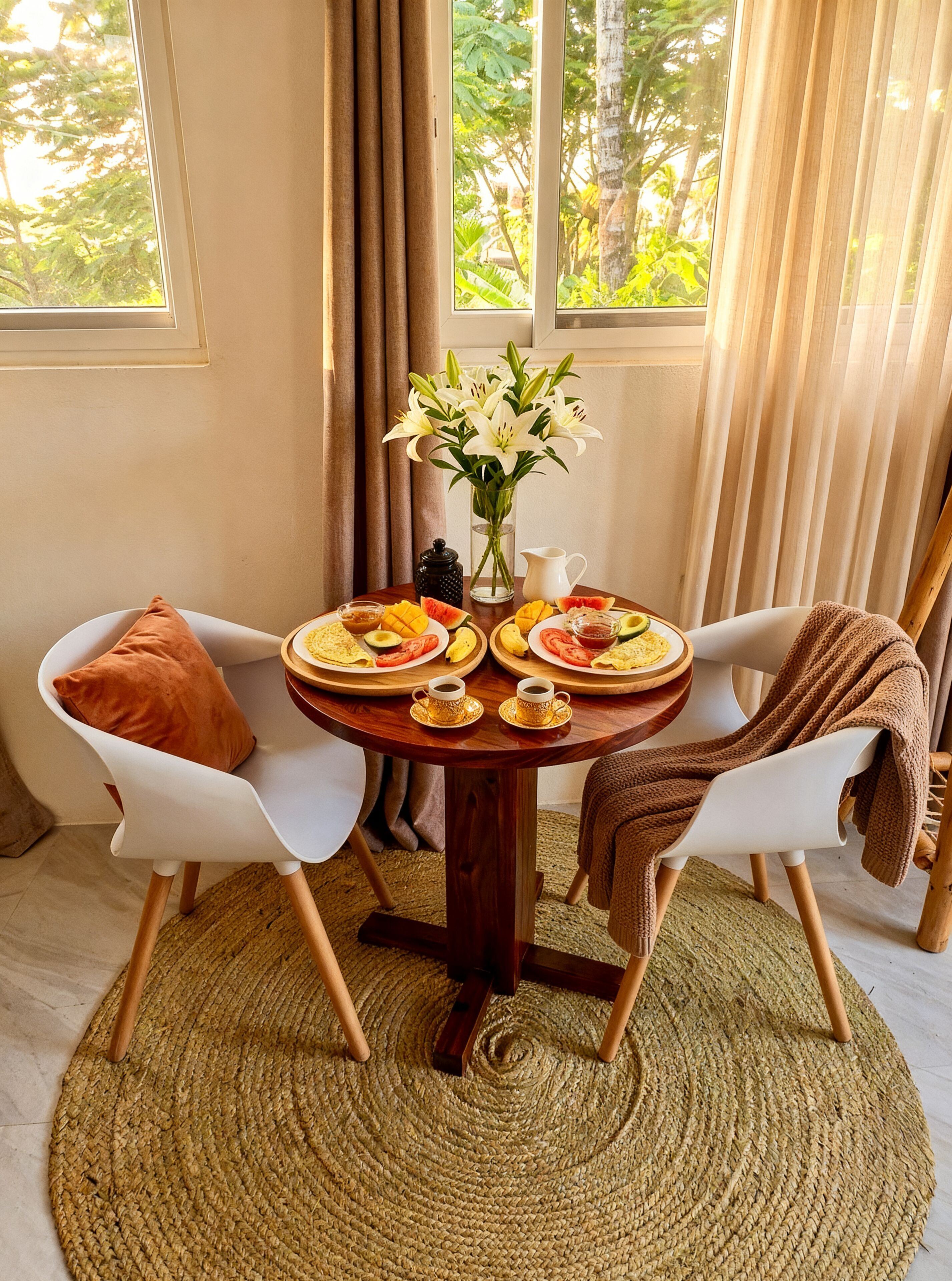 A dining table with plates of food, two chairs, a vase with flowers, and a view of trees through the window.