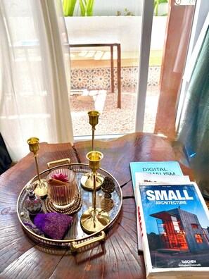 Un vassoio con oggetti decorativi e un libro intitolato "Small Architecture" su un tavolo di legno vicino a una finestra.