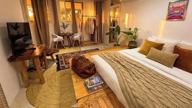 Une chambre d’hôtel équipée d’un lit, d’un bureau, d’une chaise, d’une télévision, d’une armoire et d’une fenêtre avec des rideaux.