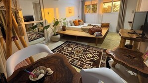 Un salon moderne avec un canapé, une table basse et une grande fenêtre agrémentée de rideaux.