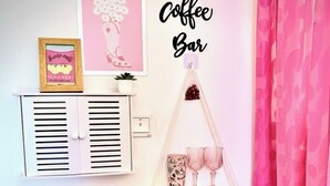 Un coin café accueillant, avec une machine à café, une tasse de café, des pâtisseries et des objets décoratifs disposés sur une table en bois.