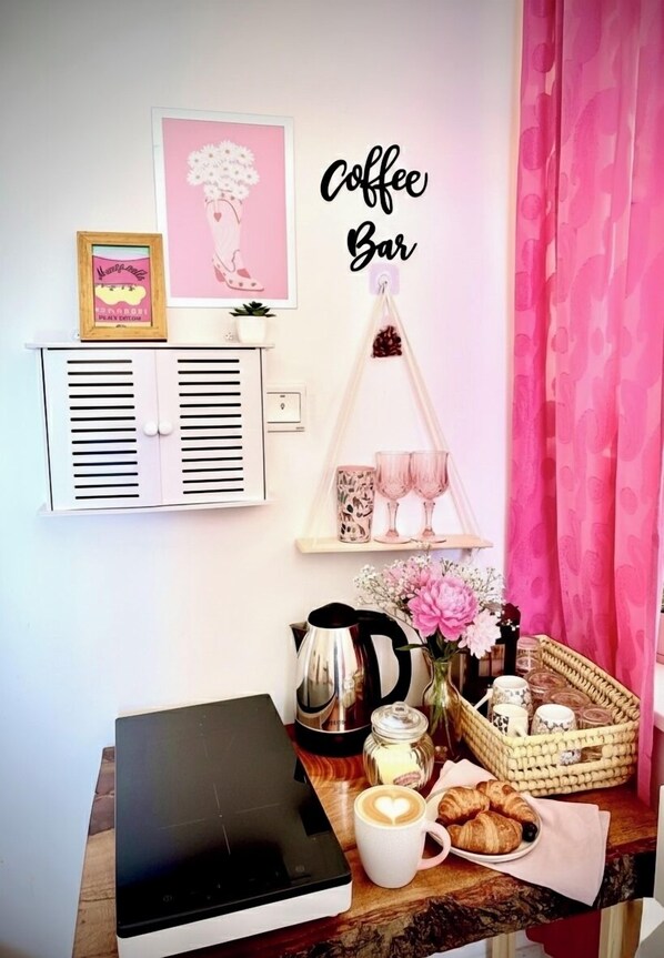 A cozy coffee bar setup with a coffee machine, a cup of coffee, pastries, and decorative items on a wooden table.