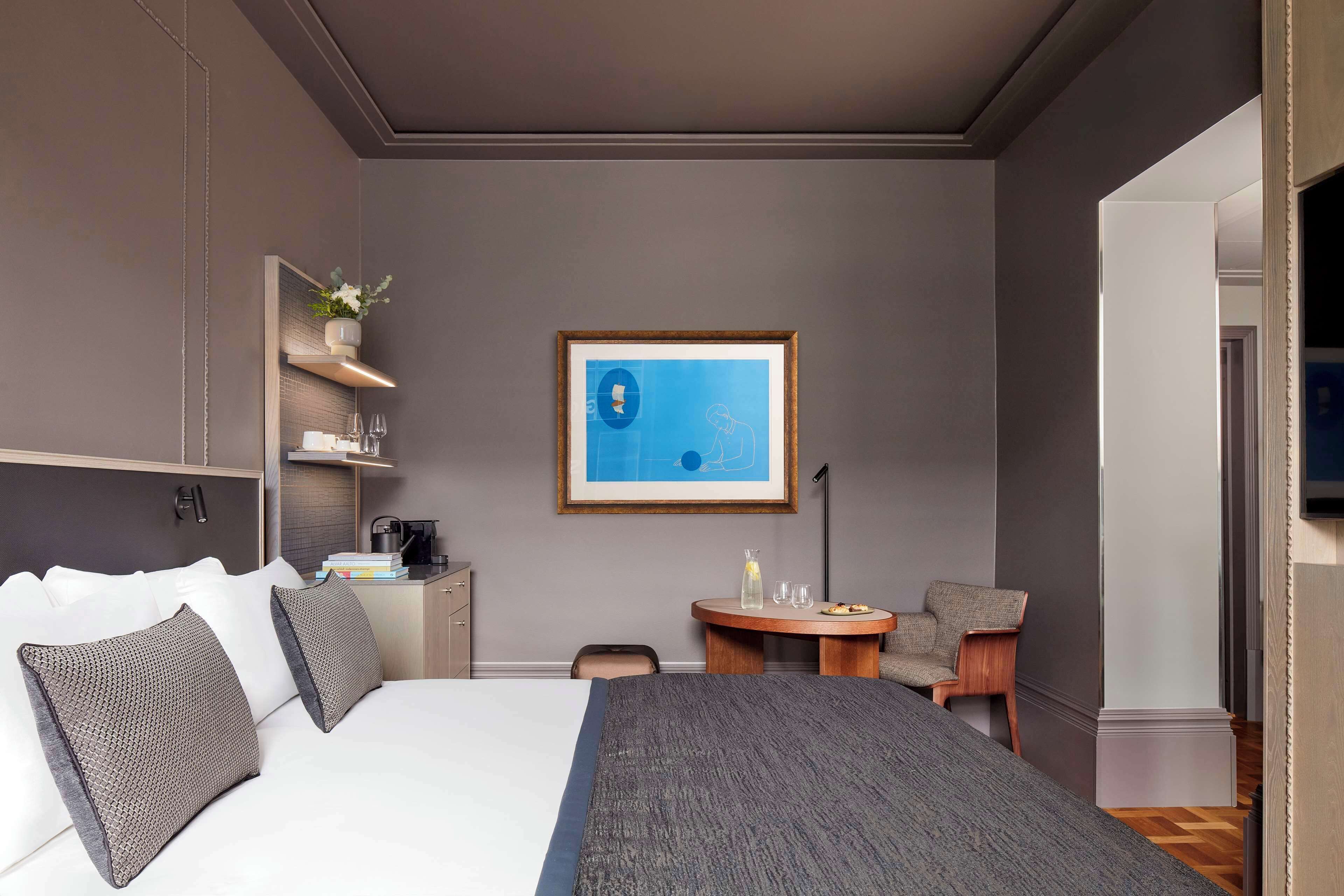 Una habitación de hotel moderna con una cama grande, un escritorio pequeño, una mesa redonda y una silla.
